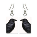 Midnight raven earrings — black raven with oil-slick sheen in cut-paper portrait, made in USA