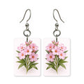 Pink blossom earrings — soft pink blossoms on a bare branch, cut-paper art, made in USA
