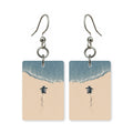 Beach hatchling earrings — baby sea turtle crossing wet sand, cut-paper art, made in USA