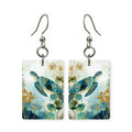 Golden sea turtle earrings — turtle lit gold through the water, cut-paper art, made in USA