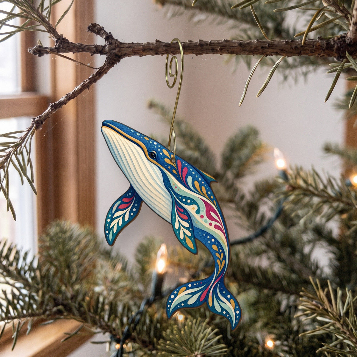 Laser-cut maple wood Fin Whale folk art ornament O101 hanging on a fir branch, made in USA