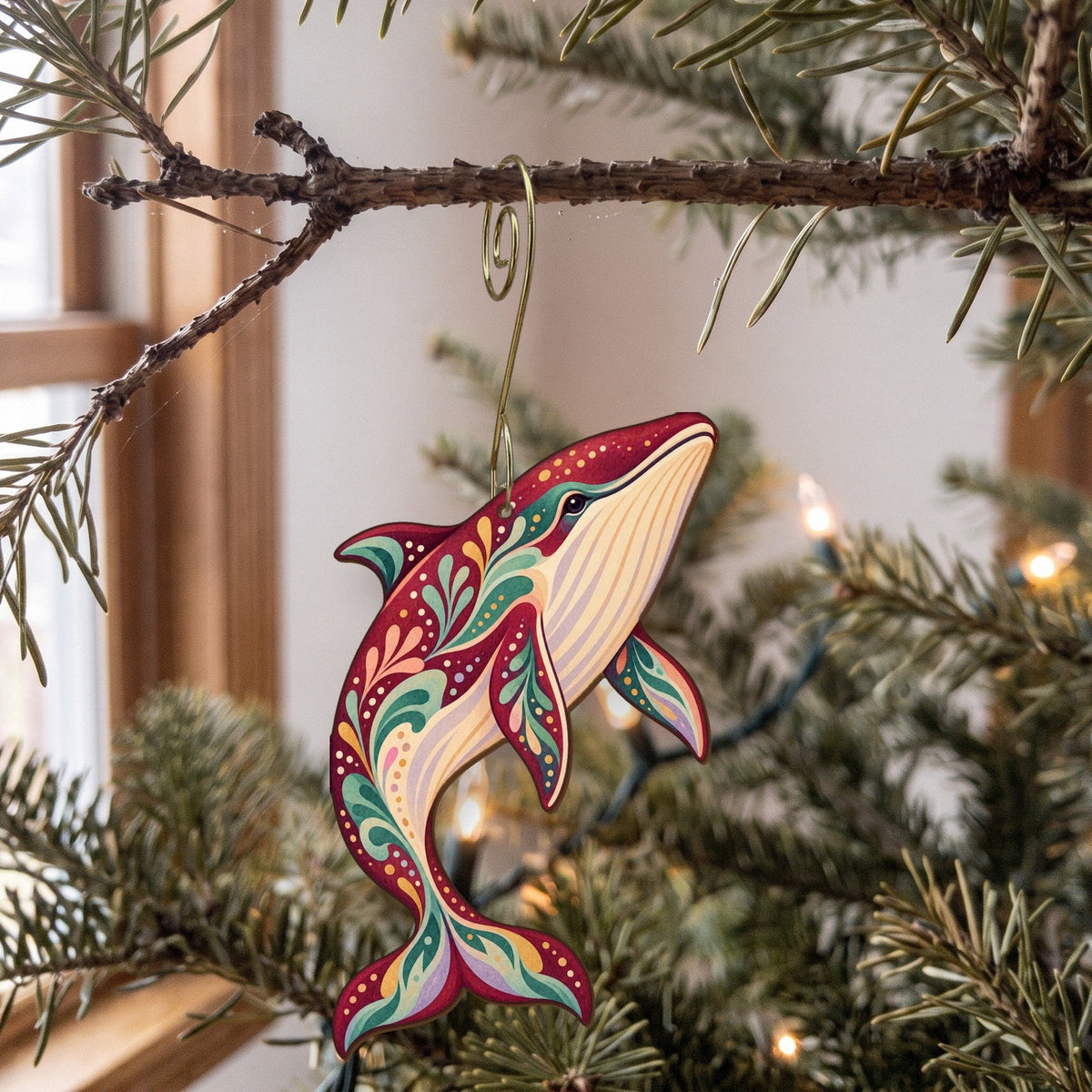 Laser-cut maple wood Minke Whale folk art ornament O102 hanging on a fir branch, made in USA