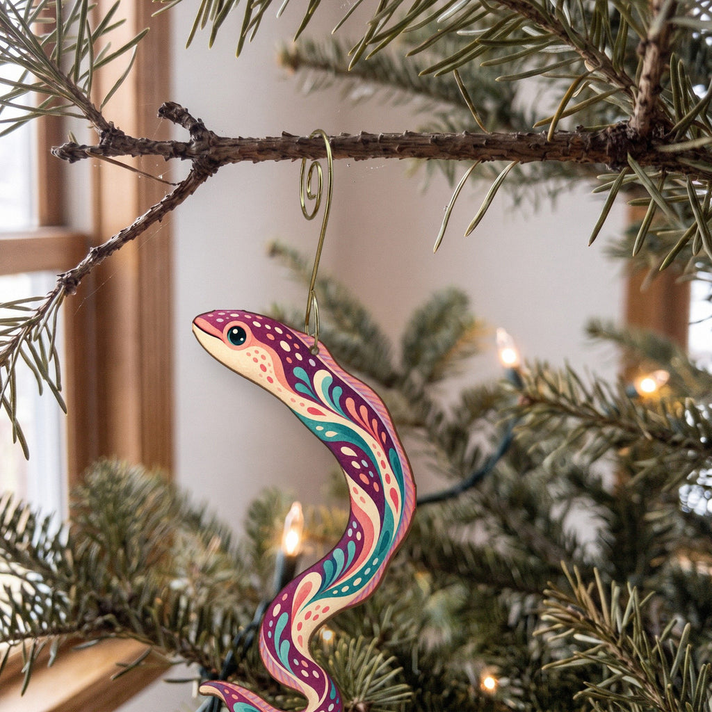 Laser-cut maple wood Garden Eel folk art ornament O148 hanging on a fir branch, made in USA