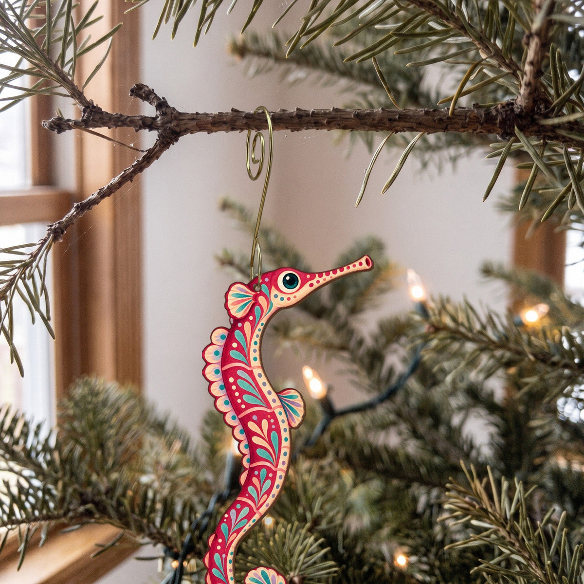 Laser-cut maple wood Pipefish folk art ornament O152 hanging on a fir branch, made in USA