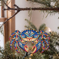 Laser-cut maple wood King Crab folk art ornament O181 hanging on a fir branch, made in USA