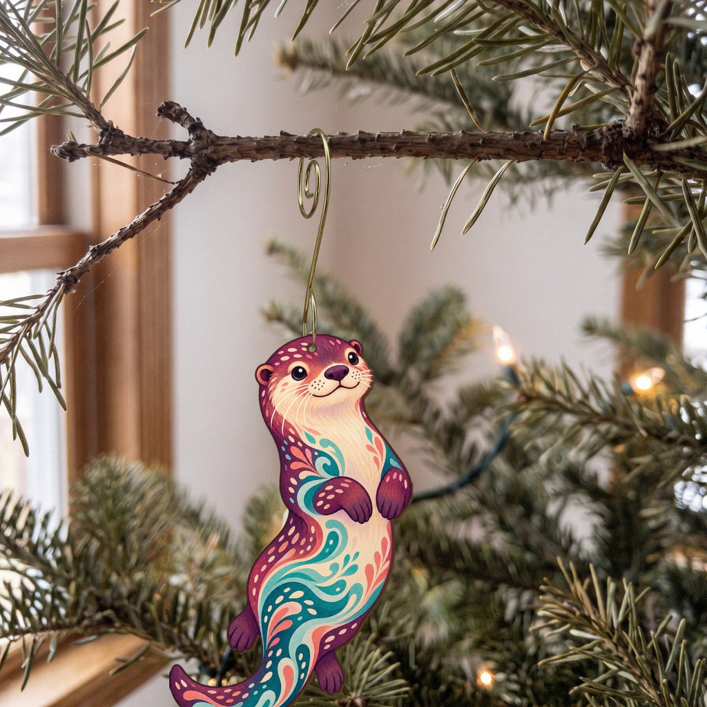 Laser-cut maple wood River Otter folk art ornament O228 hanging on a fir branch, made in USA