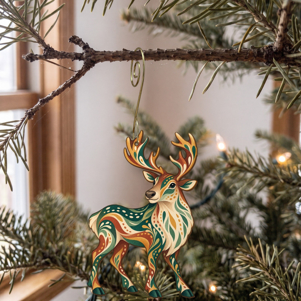 Laser-cut maple wood Caribou folk art ornament O243 hanging on a fir branch, made in USA