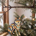 Laser-cut maple wood Gray Wolf folk art ornament O250 hanging on a fir branch, made in USA
