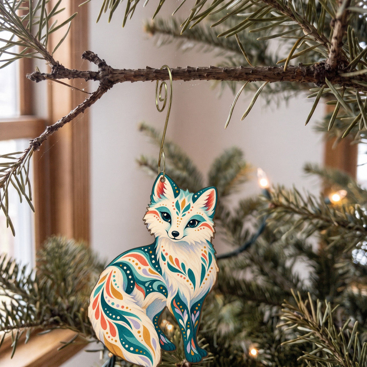 Laser-cut maple wood Arctic Fox folk art ornament O255 hanging on a fir branch, made in USA
