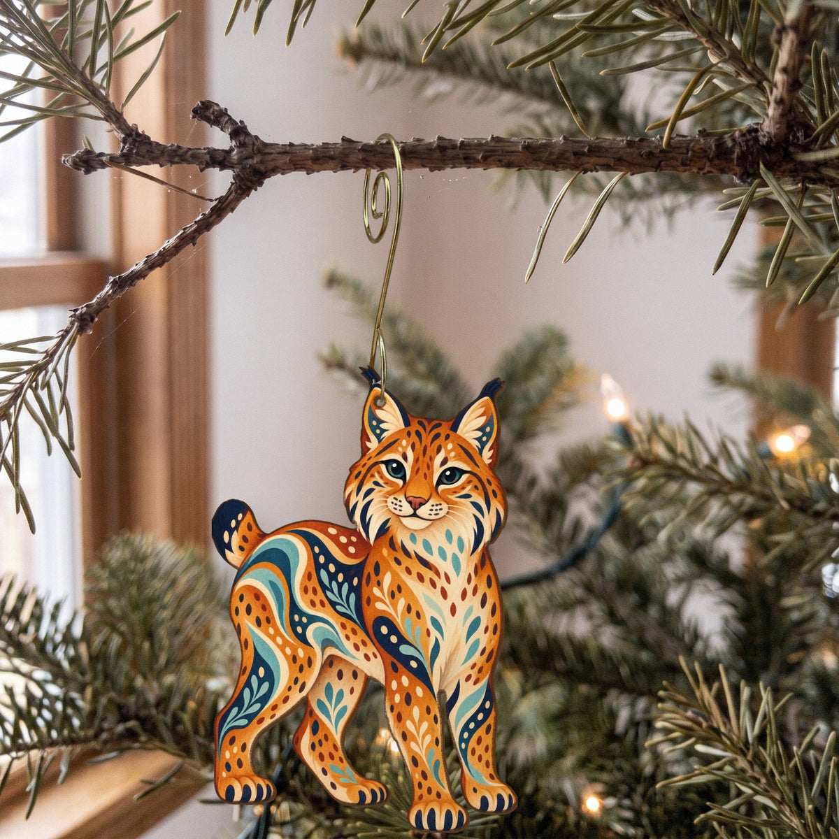 Laser-cut maple wood Bobcat folk art ornament O258 hanging on a fir branch, made in USA