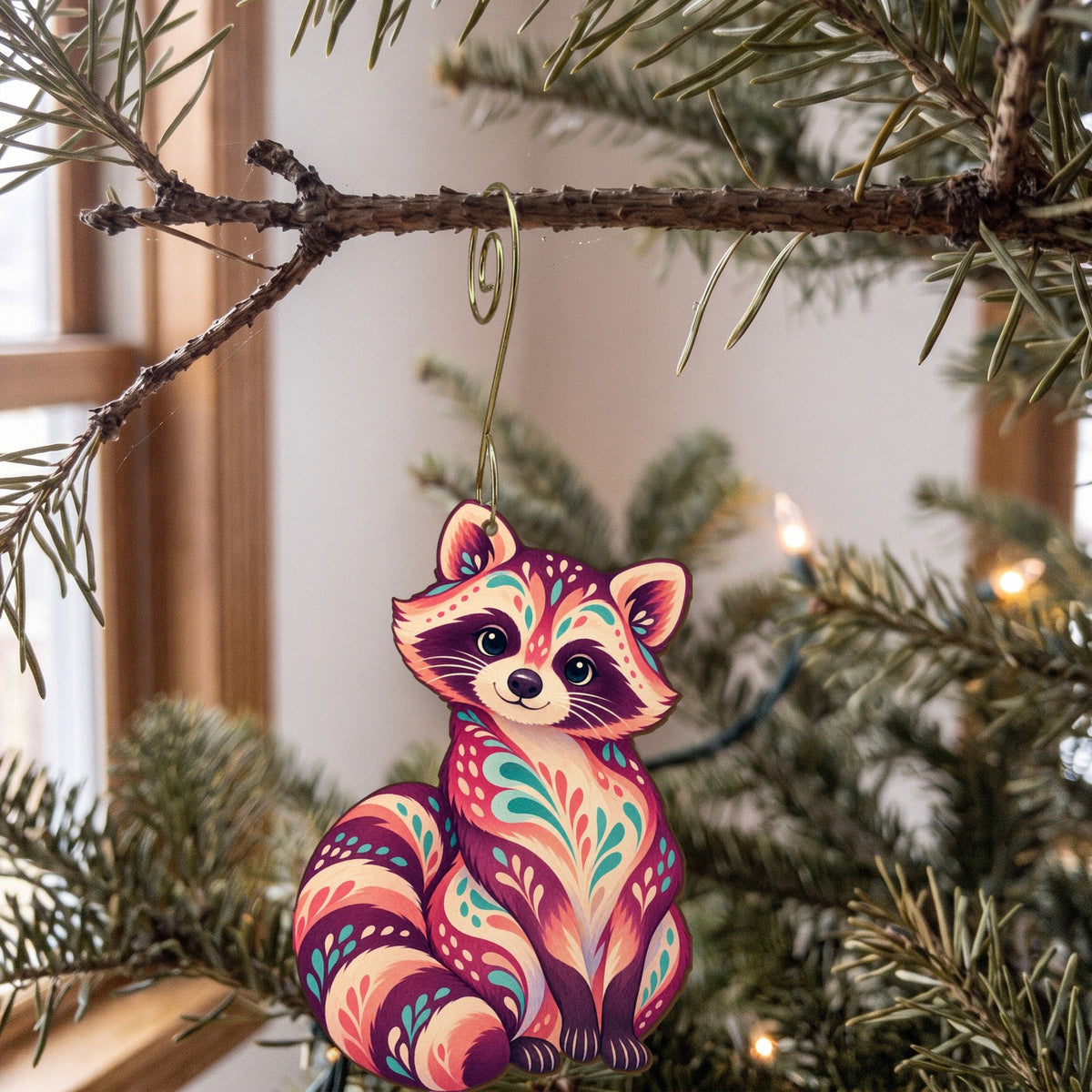 Laser-cut maple wood Raccoon folk art ornament O268 hanging on a fir branch, made in USA