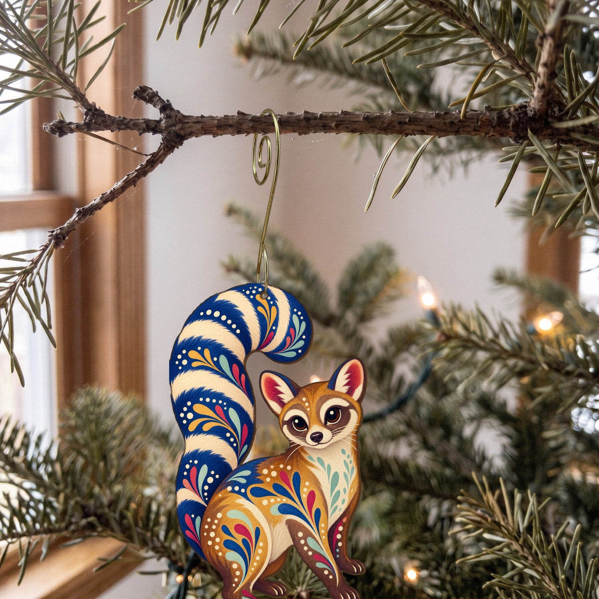Laser-cut maple wood Ringtail folk art ornament O269 hanging on a fir branch, made in USA