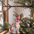 Laser-cut maple wood Snowshoe Hare folk art ornament O280 hanging on a fir branch, made in USA