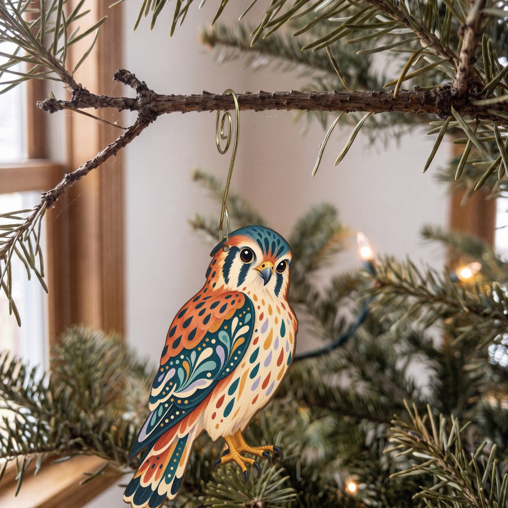 Laser-cut maple wood American Kestrel folk art ornament O295 hanging on a fir branch, made in USA