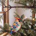 Laser-cut maple wood Bohemian Waxwing folk art ornament O309 hanging on a fir branch, made in USA