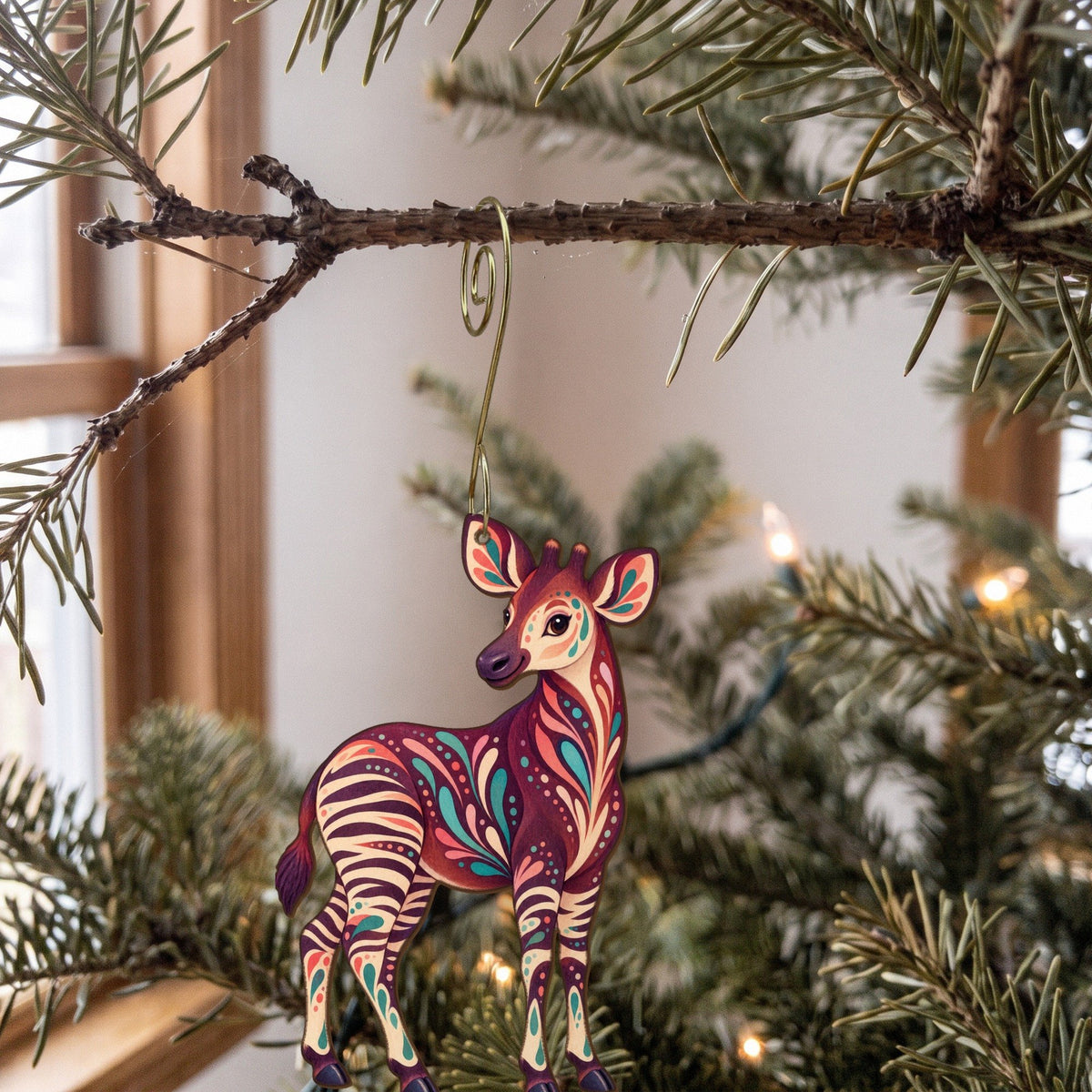 Laser-cut maple wood Okapi folk art ornament O340 hanging on a fir branch, made in USA