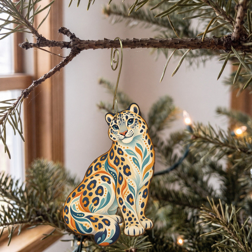 Laser-cut maple wood Snow Leopard folk art ornament O346 hanging on a fir branch, made in USA