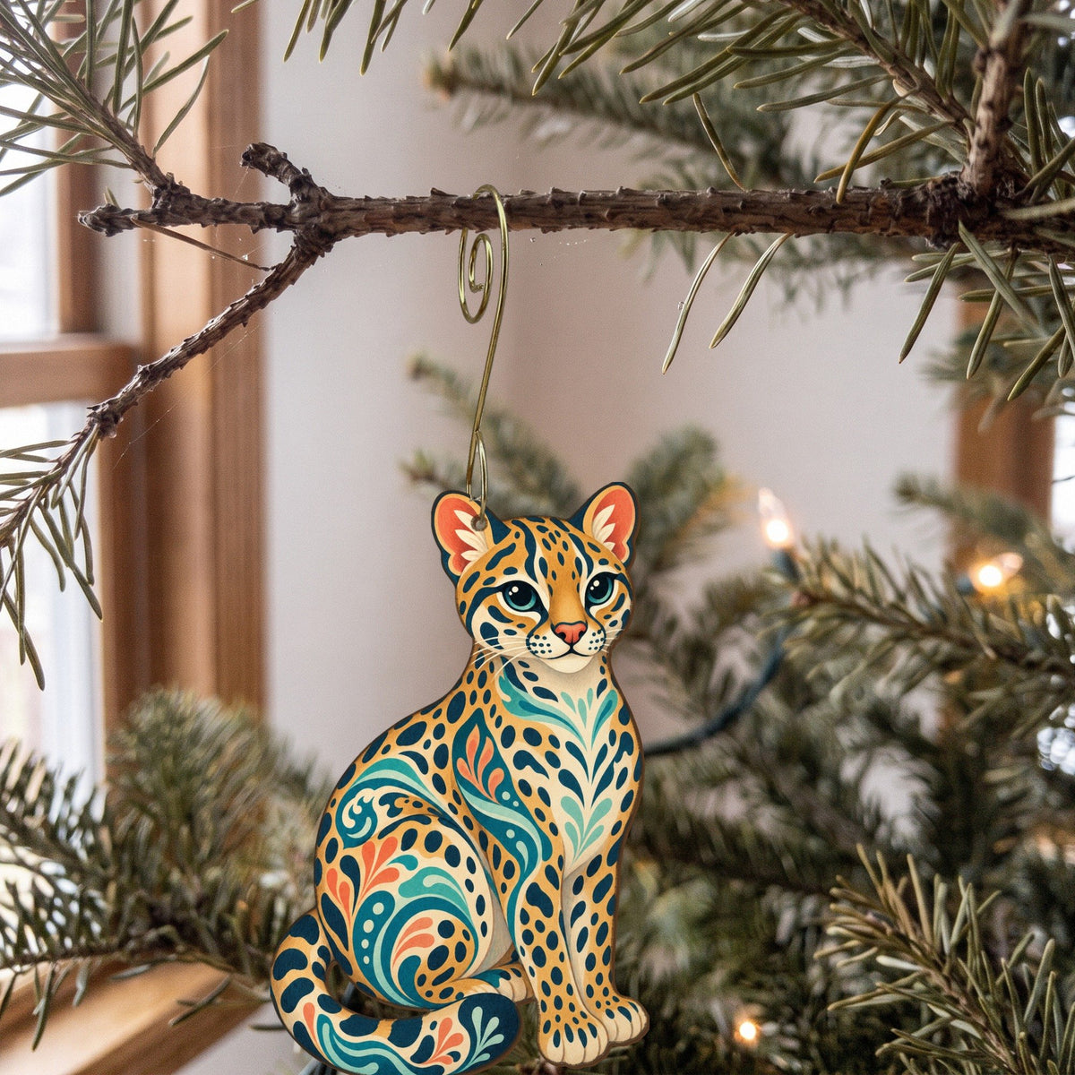 Laser-cut maple wood Ocelot folk art ornament O353 hanging on a fir branch, made in USA