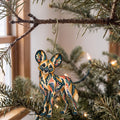 Laser-cut maple wood African Wild Dog folk art ornament O359 hanging on a fir branch, made in USA