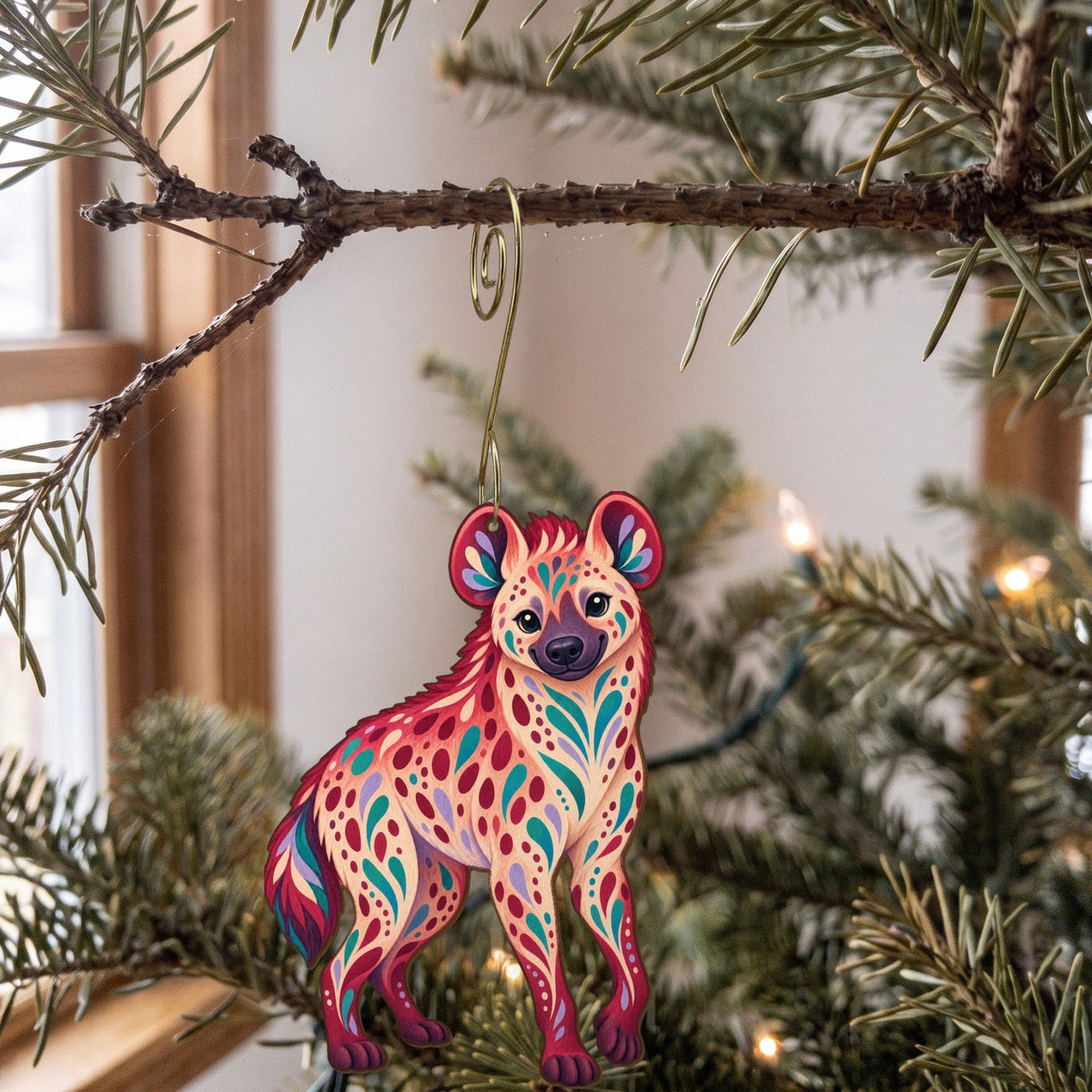 Laser-cut maple wood Spotted Hyena folk art ornament O360 hanging on a fir branch, made in USA