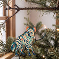 Laser-cut maple wood Striped Hyena folk art ornament O361 hanging on a fir branch, made in USA