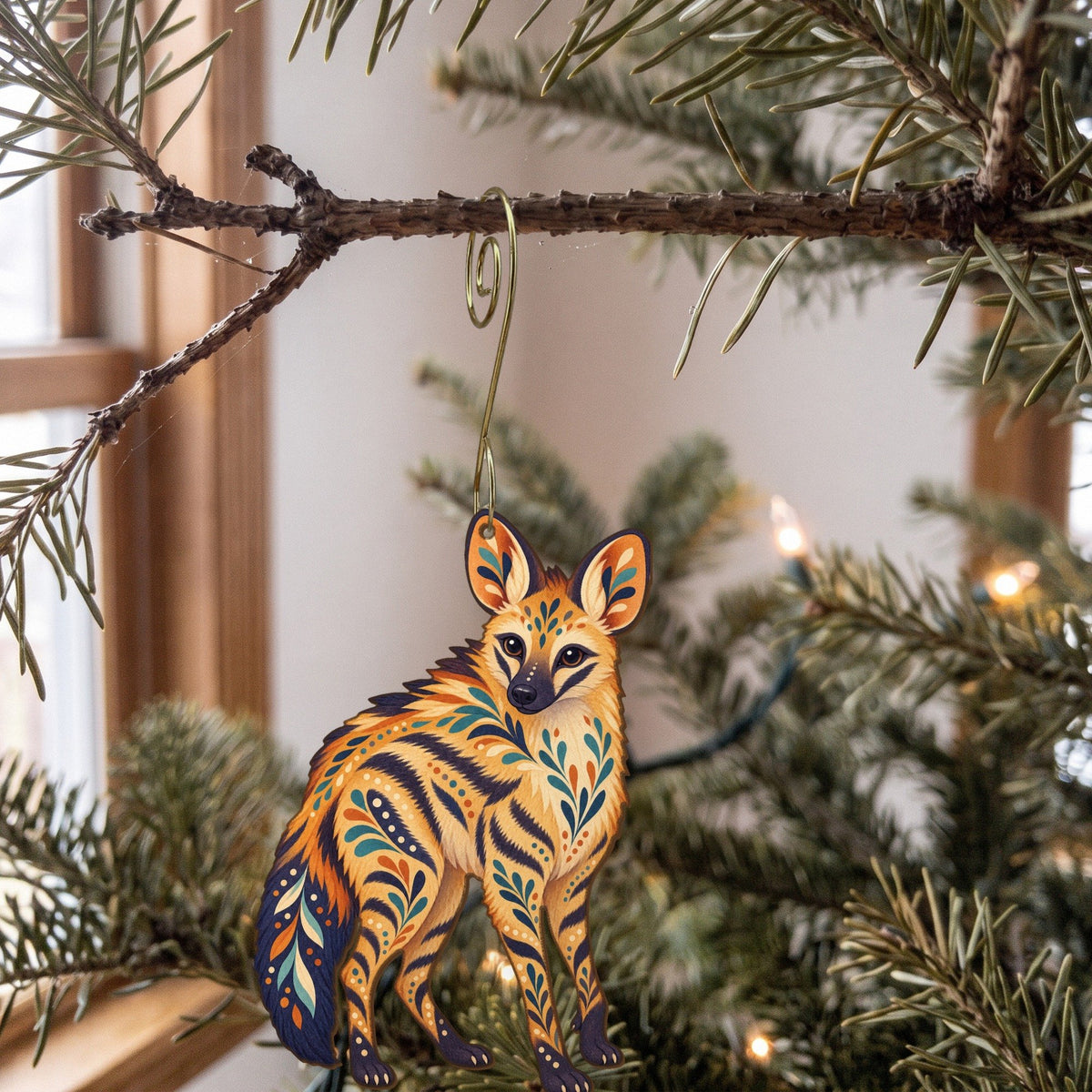 Laser-cut maple wood Aardwolf folk art ornament O362 hanging on a fir branch, made in USA
