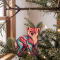 Laser-cut maple wood Bush Dog folk art ornament O364 hanging on a fir branch, made in USA