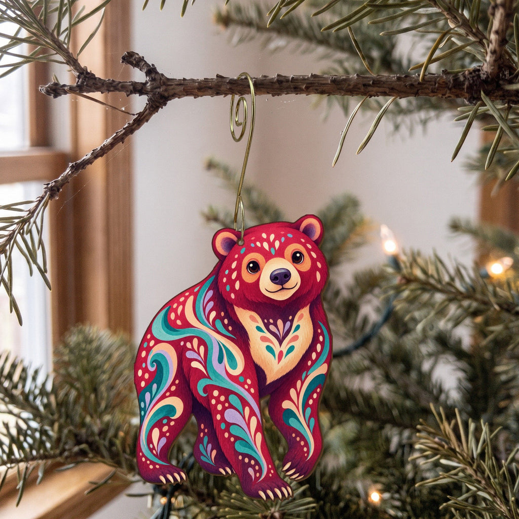Laser-cut maple wood Sun Bear folk art ornament O368 hanging on a fir branch, made in USA