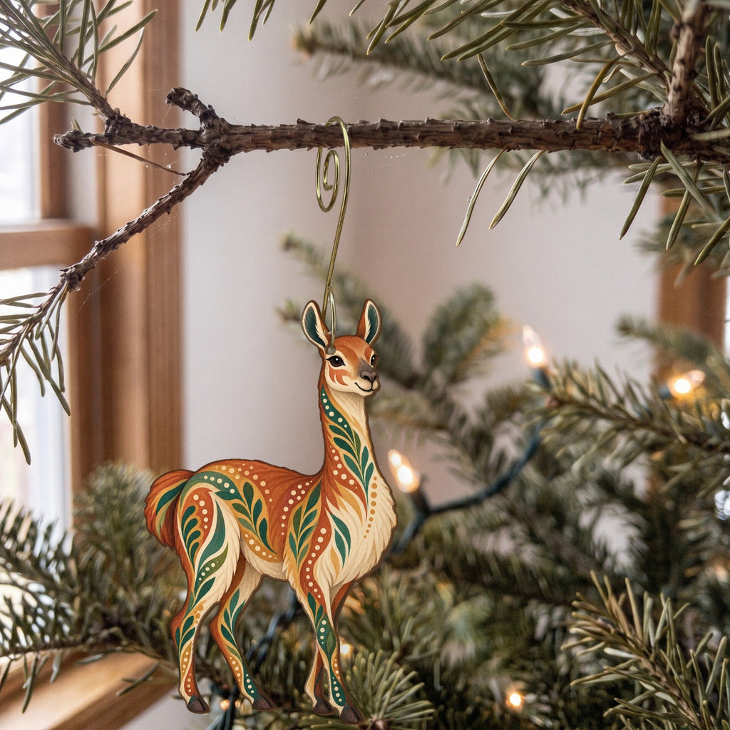 Laser-cut maple wood Guanaco folk art ornament O379 hanging on a fir branch, made in USA