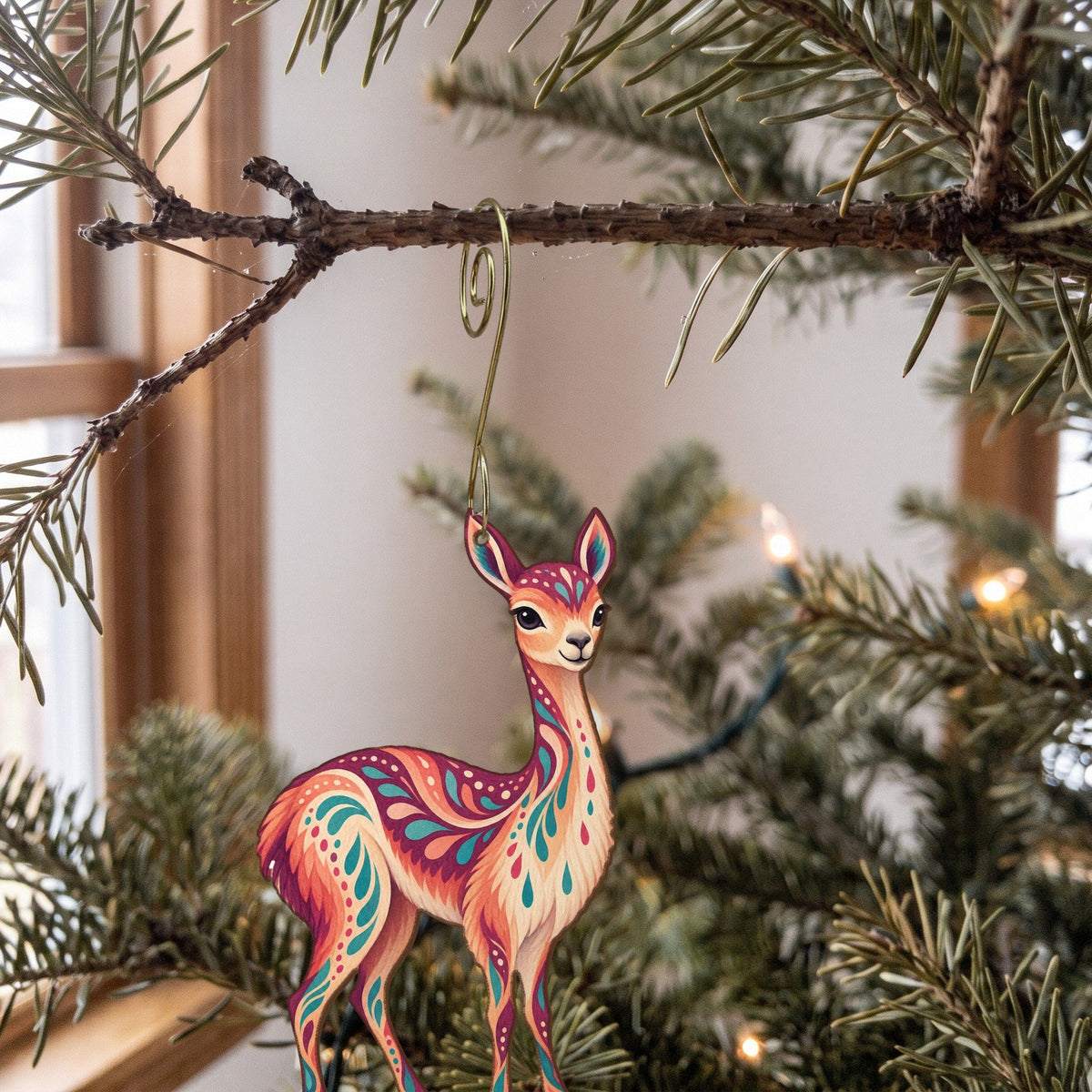 Laser-cut maple wood Vicuna folk art ornament O380 hanging on a fir branch, made in USA