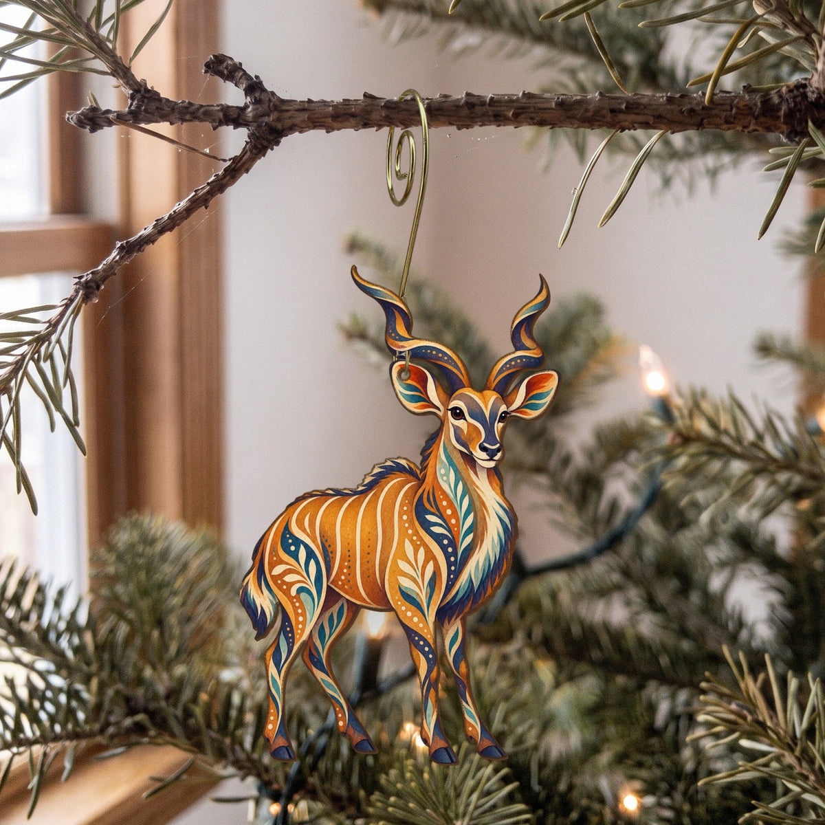 Laser-cut maple wood Greater Kudu folk art ornament O386 hanging on a fir branch, made in USA
