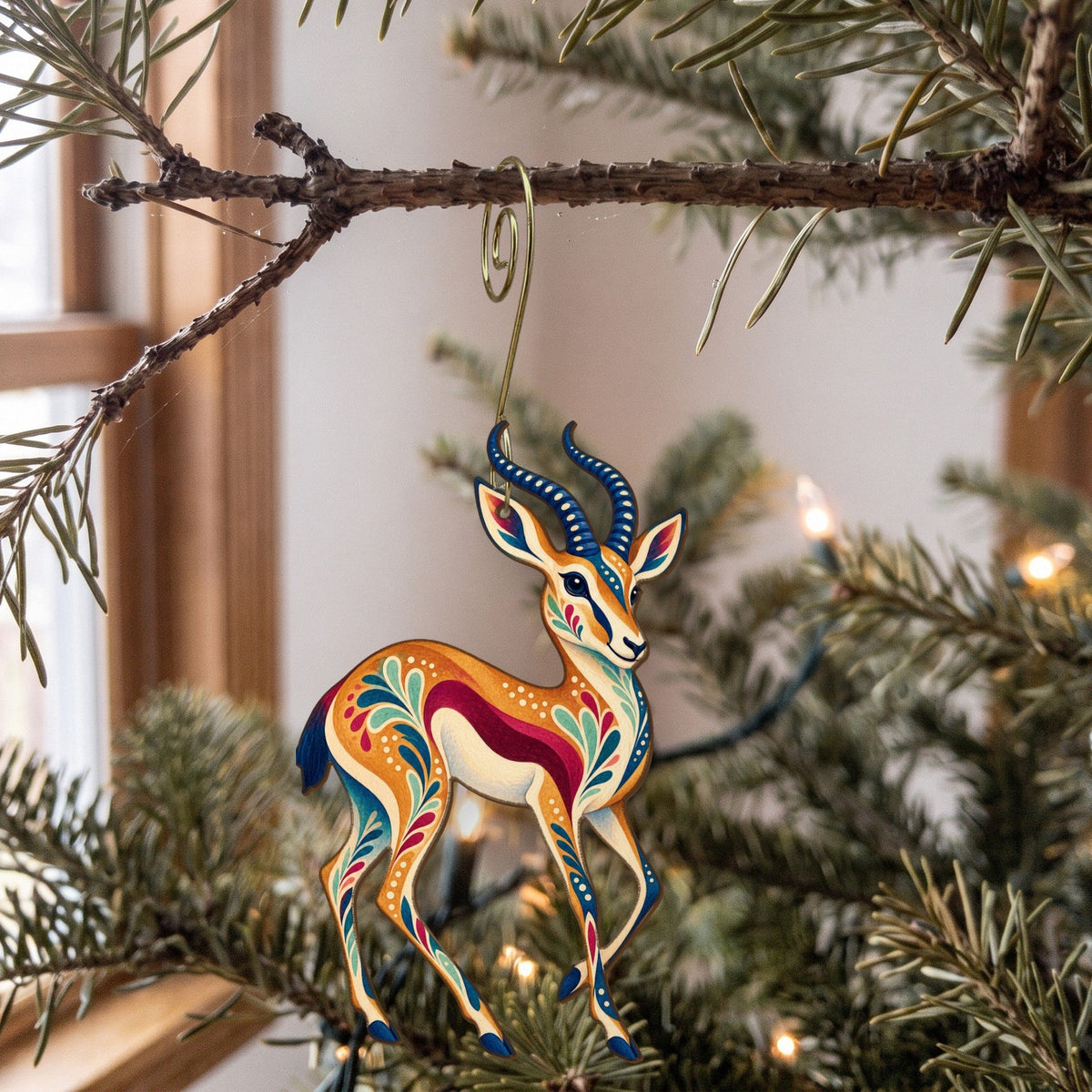 Laser-cut maple wood Springbok folk art ornament O389 hanging on a fir branch, made in USA