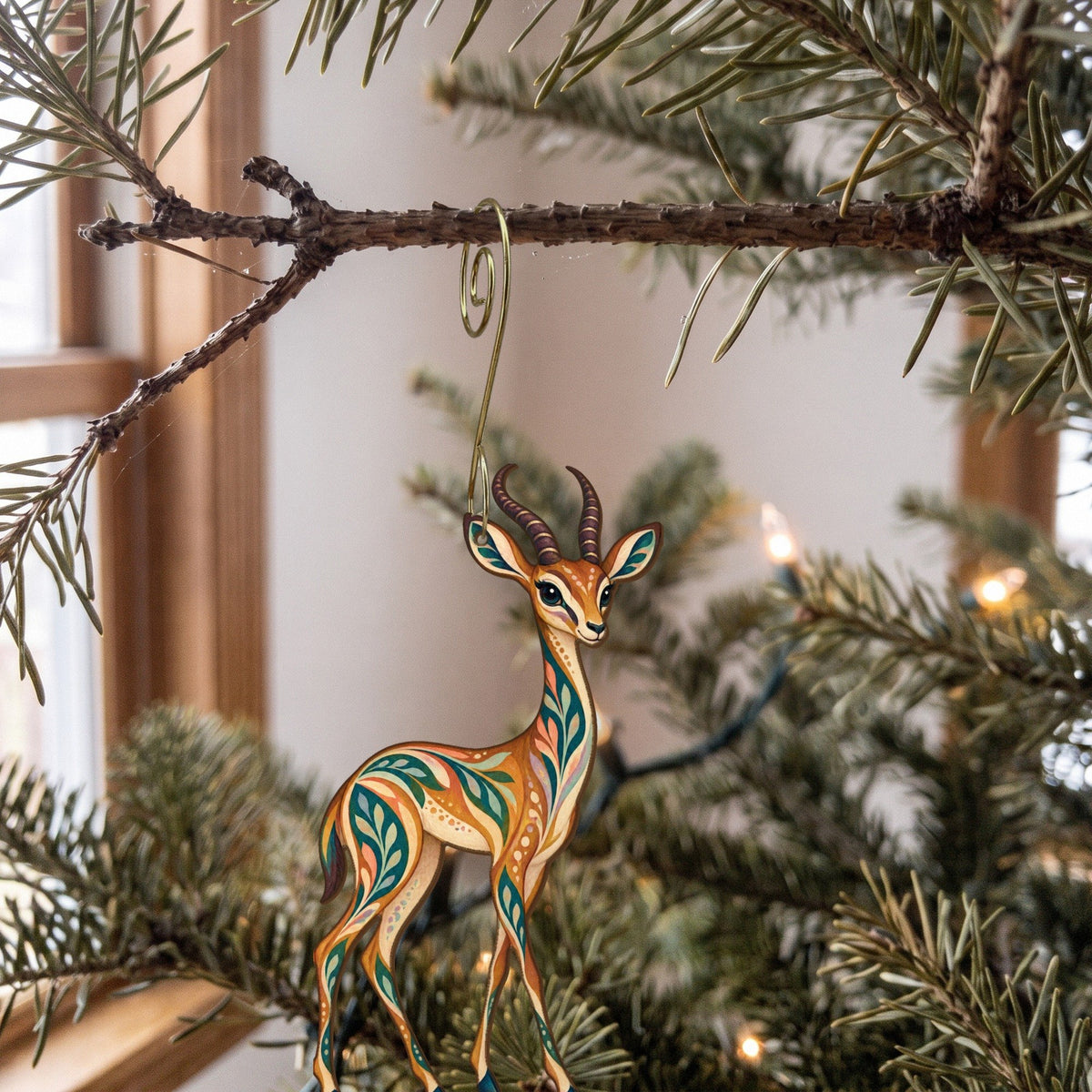 Laser-cut maple wood Gerenuk folk art ornament O391 hanging on a fir branch, made in USA