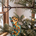 Laser-cut maple wood Kinkajou folk art ornament O409 hanging on a fir branch, made in USA