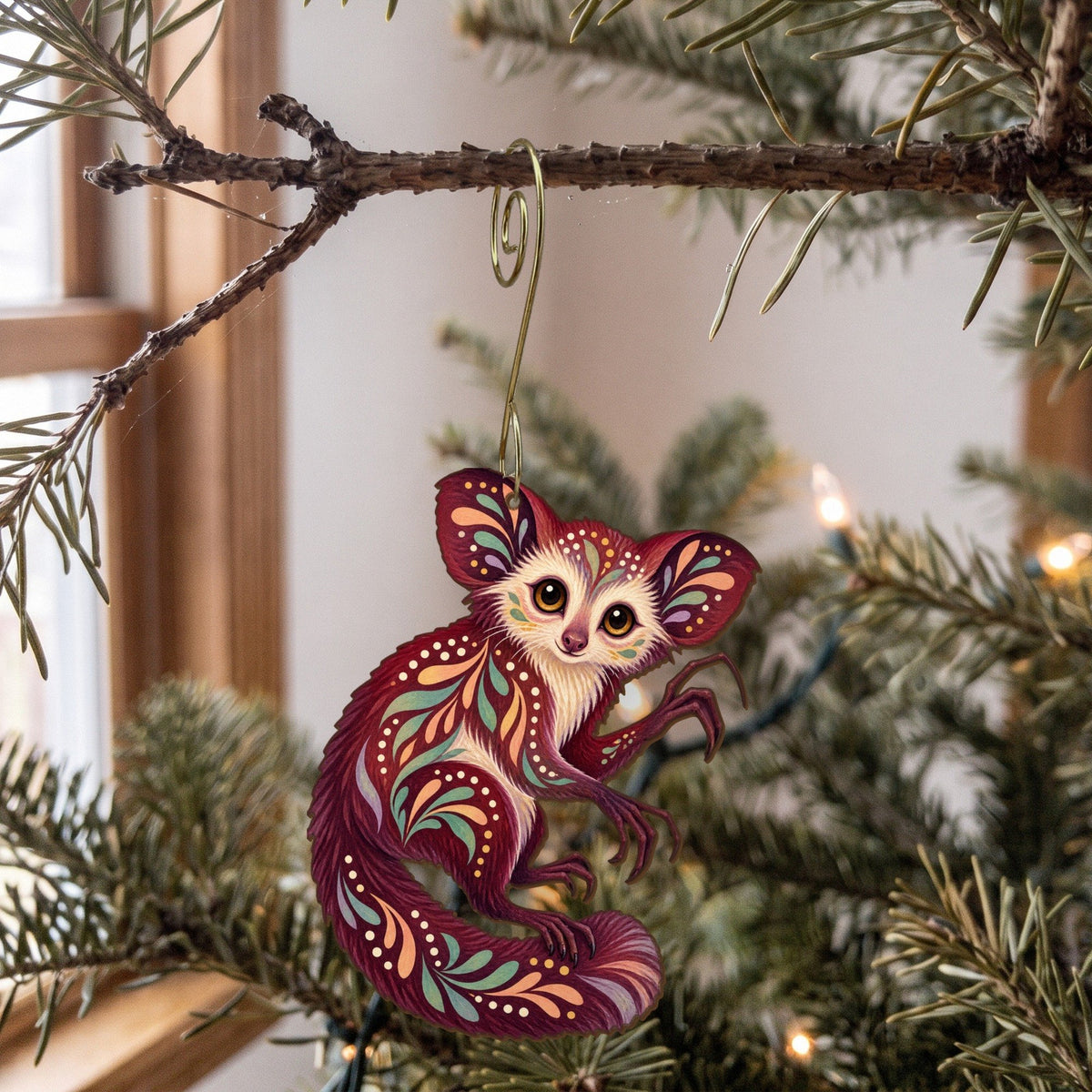 Laser-cut maple wood Aye-Aye folk art ornament O414 hanging on a fir branch, made in USA