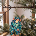 Laser-cut maple wood Chimpanzee folk art ornament O417 hanging on a fir branch, made in USA