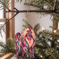 Laser-cut maple wood Gelada folk art ornament O420 hanging on a fir branch, made in USA