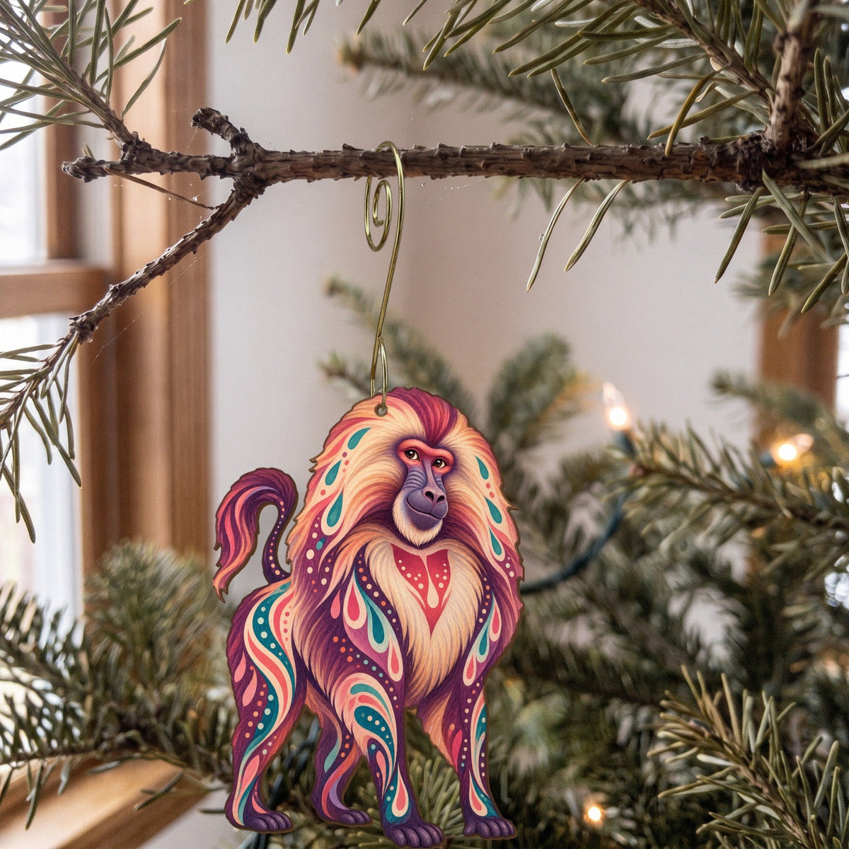 Laser-cut maple wood Gelada folk art ornament O420 hanging on a fir branch, made in USA