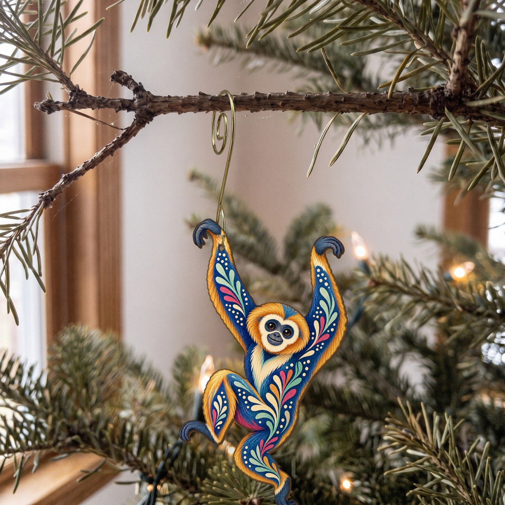 Laser-cut maple wood Gibbon folk art ornament O429 hanging on a fir branch, made in USA