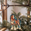 Laser-cut maple wood Clydesdale Horse folk art ornament O479 hanging on a fir branch, made in USA