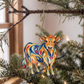 Laser-cut maple wood Jersey Cow folk art ornament O485 hanging on a fir branch, made in USA