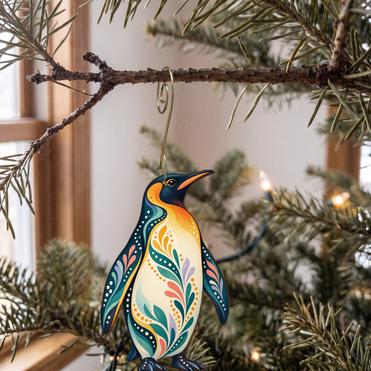 Laser-cut maple wood King Penguin folk art ornament O519 hanging on a fir branch, made in USA